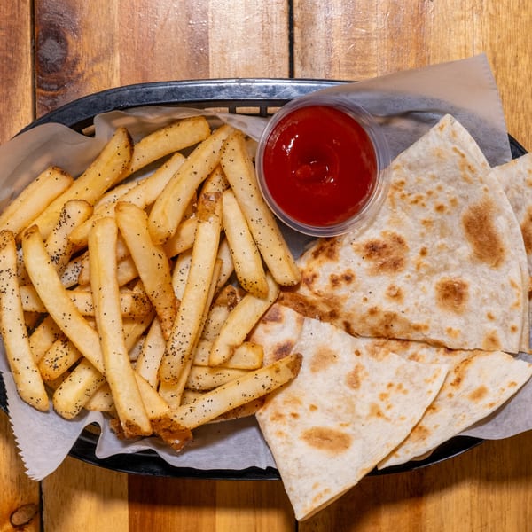 Basket of golden fries with pepper, a side of ketchup, and cheese quesadilla triangles.