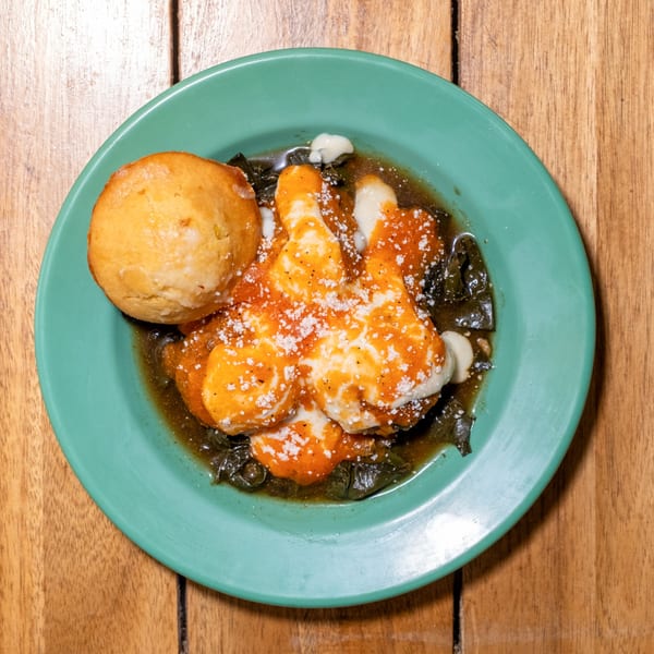 Overhead view of a green plate with a golden biscuit and eggs covered in orange sauce.